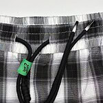 Close-up of plaid shorts with black drawstring and elastic waistband, suitable for casual wear and comfortable fashion.