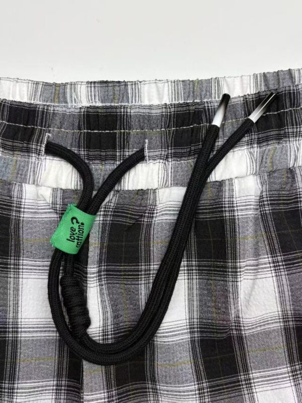 Close-up of plaid shorts with black drawstring and elastic waistband, suitable for casual wear and comfortable fashion.