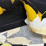 Close-up of fabric featuring a bold yellow and black floral pattern, showcasing detailed stitching and textile texture.