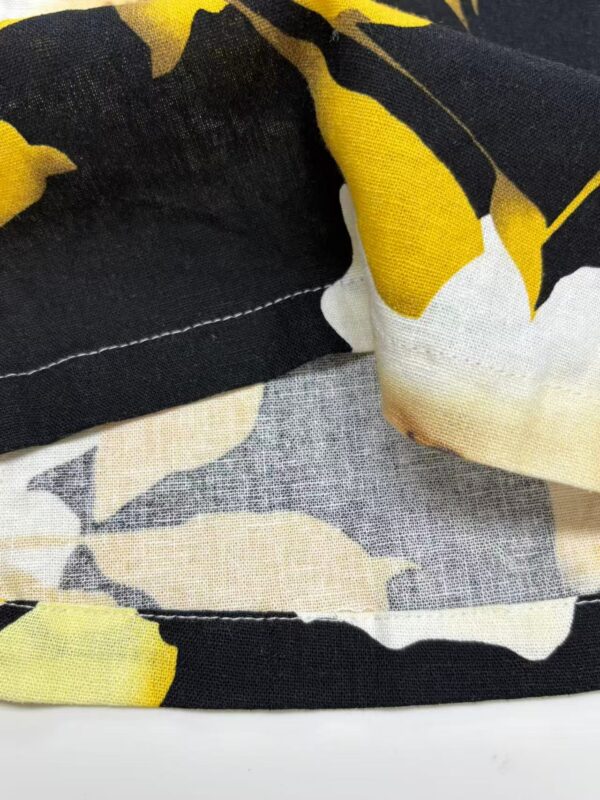 Close-up of fabric featuring a bold yellow and black floral pattern, showcasing detailed stitching and textile texture.