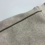 Detailed close-up of a beige woolen sweater showing texture and stitching details.