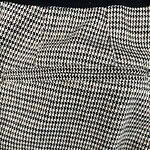 Close-up of houndstooth fabric with detailed pattern in black, white, and beige tones, showcasing texture and weave.