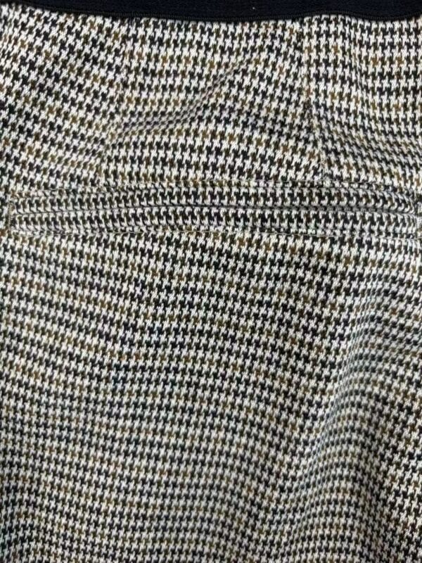 Close-up of houndstooth fabric with detailed pattern in black, white, and beige tones, showcasing texture and weave.