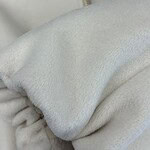 Detailed close-up of soft white fleece fabric, highlighting its plush texture and cozy appearance, suitable for winter clothing or blankets.