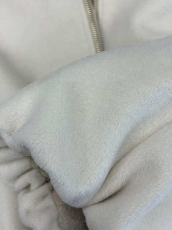 Detailed close-up of soft white fleece fabric, highlighting its plush texture and cozy appearance, suitable for winter clothing or blankets.