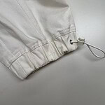 Close-up of white fabric with drawstring and elastic hem, suitable for sportswear or casual clothing.
