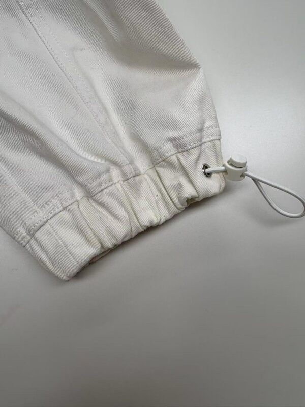 Close-up of white fabric with drawstring and elastic hem, suitable for sportswear or casual clothing.