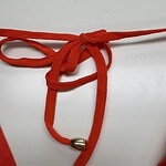 Close-up of a red cord necklace with silver beads, tied in a bow, on a white background, showcasing stylish jewelry design.