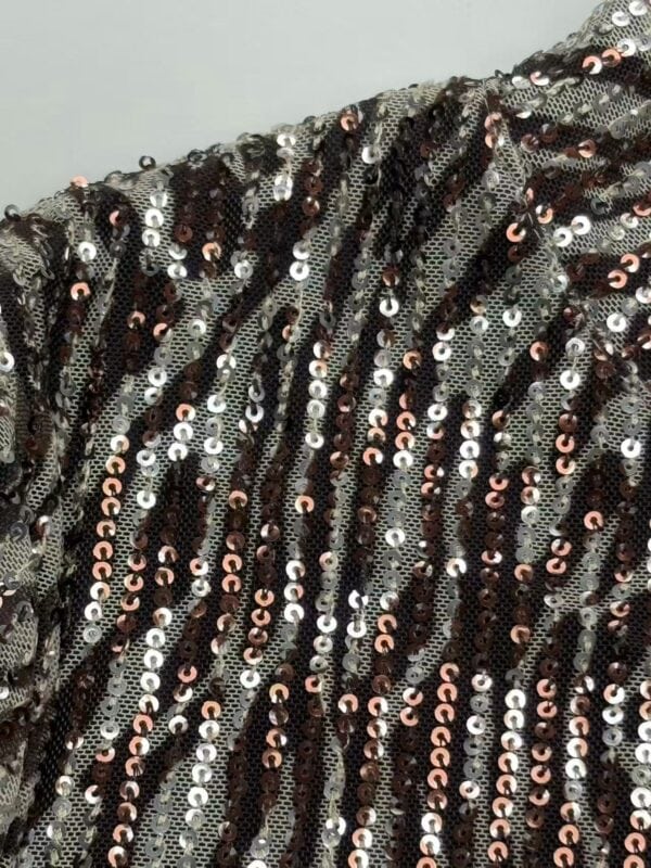 Close-up of sequin fabric featuring black, silver, and rose gold sequins arranged in wavy patterns for a glamorous look.