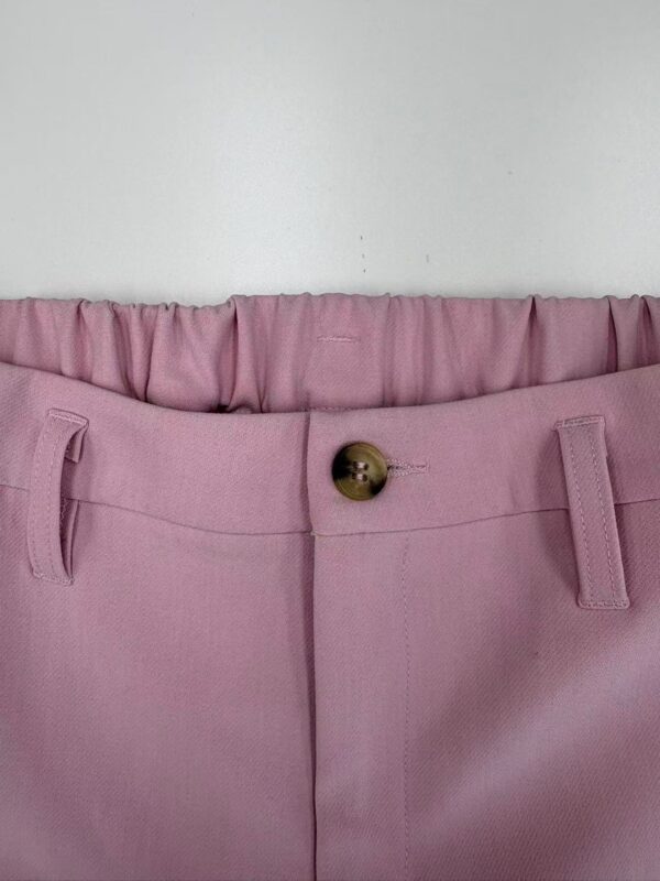 Close-up of pink women's trousers with a button and belt loops, showcasing stylish and comfortable fashion wear.