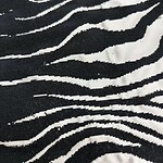 Close-up of black and white zebra print fabric, showcasing wavy stripes and textured material, ideal for stylish clothing and accessories.