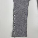 Close-up of a gray knit sweater sleeve featuring a row of five buttons and a small slit at the cuff, showcasing detailed craftsmanship and soft fabric.