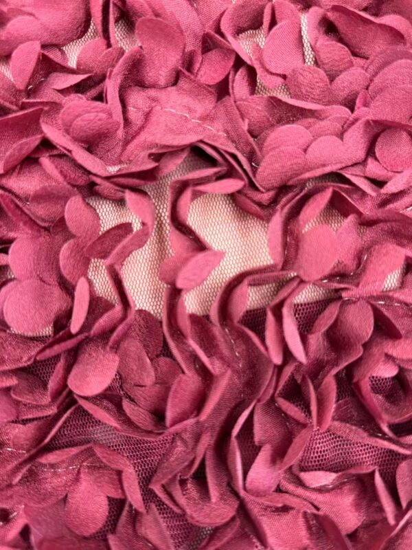 Close-up of pink ruffled fabric with layered petal-like textures, showcasing intricate design and vibrant color for fashion and textile focus.