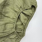 Close-up of olive green linen fabric with elastic edge, showing texture and stitching details for fashion and textile SEO.
