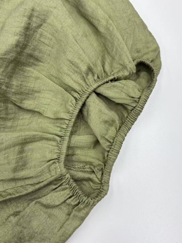 Close-up of olive green linen fabric with elastic edge, showing texture and stitching details for fashion and textile SEO.