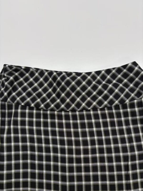 Close-up of a black and white checkered skirt with a high waist, showcasing a classic pattern suitable for casual or office wear.