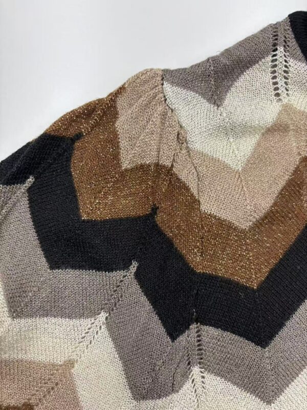 Close-up of a multicolored knit sweater featuring earthy tones like beige, brown, black, and cream, showcasing intricate patterns and textured fabric.