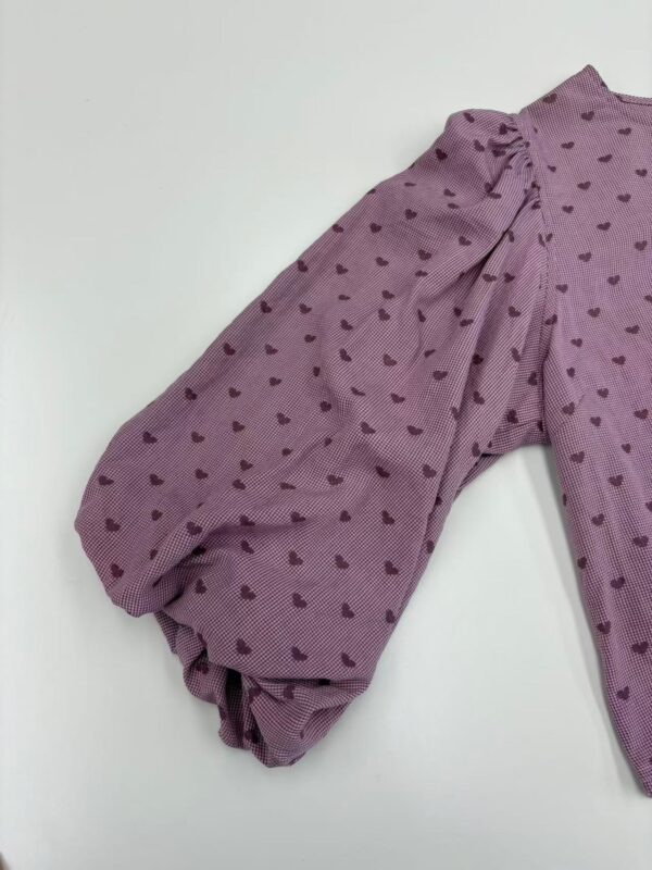 Elegant purple blouse with black heart pattern, featuring puffed sleeves and high neckline, perfect for casual or semi-formal occasions.