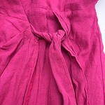 Close-up of a vibrant pink linen dress featuring a tied waist detail, showcasing soft fabric texture and elegant design for stylish summer wear.