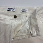 Close-up of cream-colored men's chino pants with zipper and button closure, showing fabric texture and fit details.