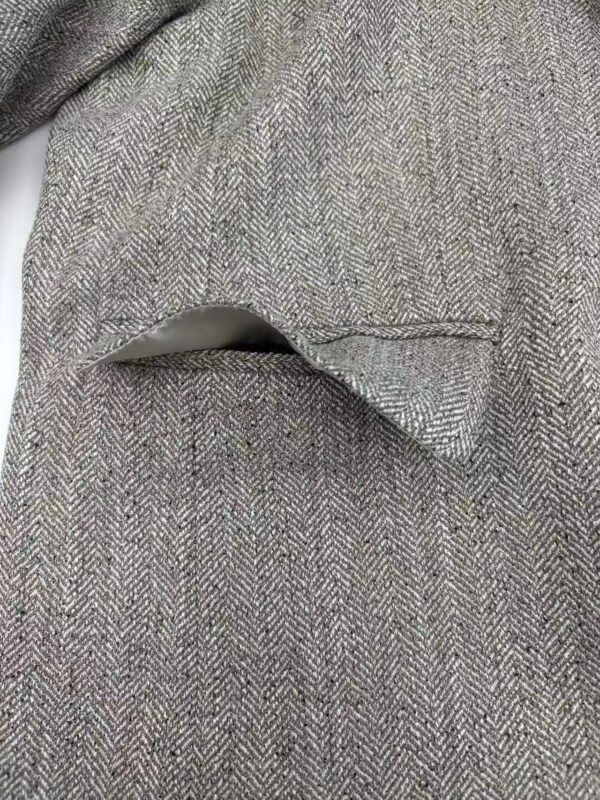 Close-up of a classic herringbone wool coat with a tailored pocket detail, showcasing high-quality fabric and craftsmanship for stylish winter wear.