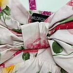 Close-up of floral fabric with pink, green, and red colors, featuring a bow and a WILDFOX label, suitable for fashion and clothing SEO.