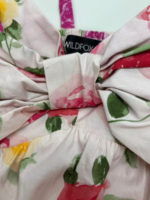 Close-up of floral fabric with pink, green, and red colors, featuring a bow and a WILDFOX label, suitable for fashion and clothing SEO.