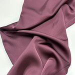 Close-up of luxurious mauve satin fabric with smooth texture and gentle folds, ideal for high-end clothing and fashion design.