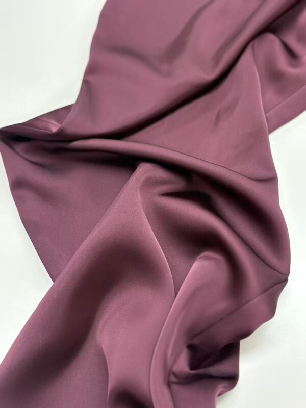 Close-up of luxurious mauve satin fabric with smooth texture and gentle folds, ideal for high-end clothing and fashion design.