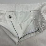 Close-up of stylish white pants with zipper and button details, perfect for modern fashion looks.