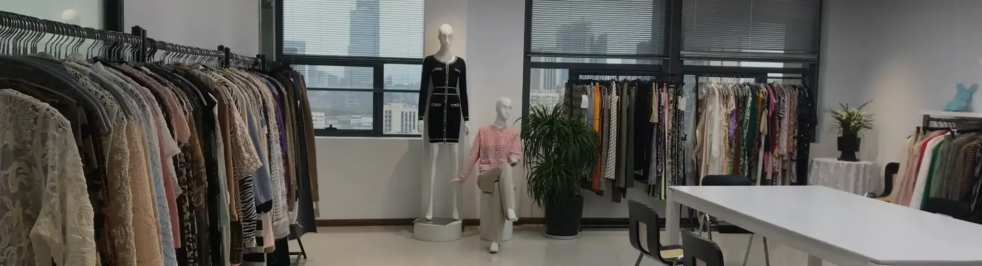 Interior of a fashion boutique showcasing clothing racks filled with various garments and mannequins displaying outfits, with large windows and modern decor.