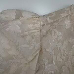 Close-up of a beige wall with a rough, textured surface and layered paint or plaster finish.