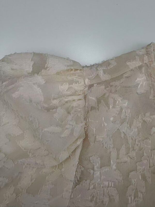 Close-up of a beige wall with a rough, textured surface and layered paint or plaster finish.
