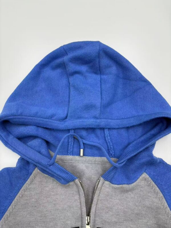 Close-up of a blue and gray hoodie with a zipper and drawstrings, casual streetwear style.
