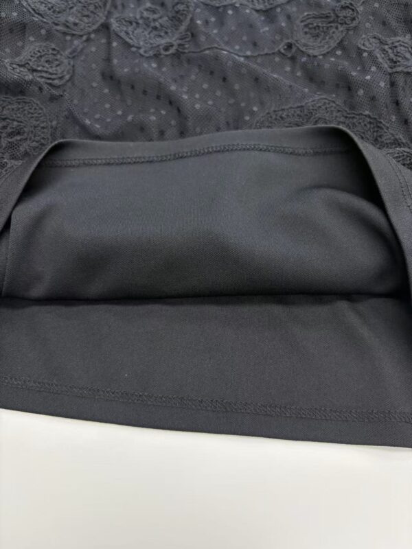 Close-up of a black lace dress with intricate lace details and a smooth satin skirt, perfect for formal occasions and evening wear.