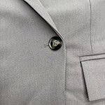 Close-up of a grey suit jacket with a single button and tailored lapel, showcasing professional men's fashion and formal wear.