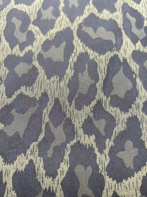 Close-up of leopard print fabric with dark gray and beige pattern, ideal for stylish clothing and accessories.