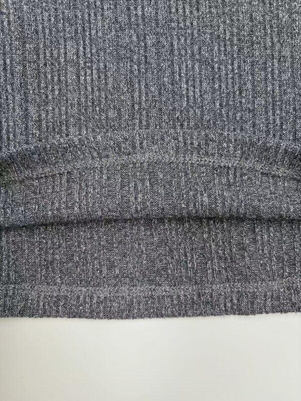 Detailed close-up of grey fabric with fine texture, suitable for clothing or upholstery, showcasing the weave pattern and fabric quality.