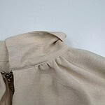 Close-up of a beige blouse featuring puffed sleeves and a zipper detail, perfect for stylish casual or office wear.