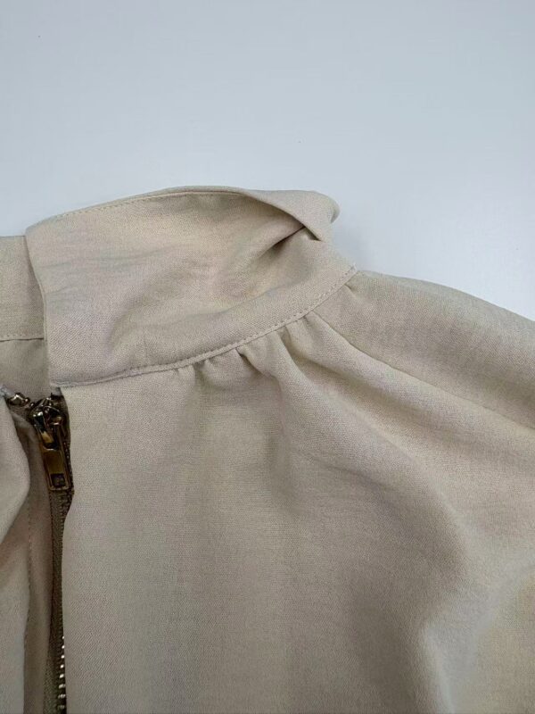 Close-up of a beige blouse featuring puffed sleeves and a zipper detail, perfect for stylish casual or office wear.