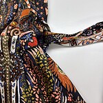Vibrant bohemian patterned scarf with intricate designs in orange, blue, black, and white, tied in a knot on a white background.