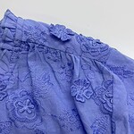 Close-up of a blue embroidered dress showcasing intricate floral and leaf patterns with textured embroidery work.