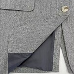 Close-up of men's herringbone wool blazer with a single button and inner lining, showcasing classic tailored design and high-quality fabric.