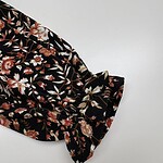 Close-up of black fabric with intricate floral pattern and bow detail, suitable for fashion or textile design.
