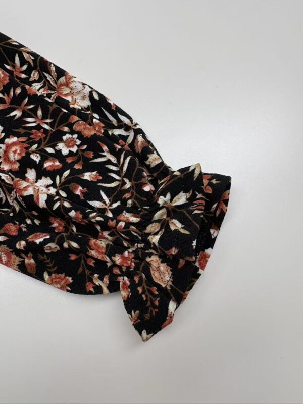 Close-up of black fabric with intricate floral pattern and bow detail, suitable for fashion or textile design.