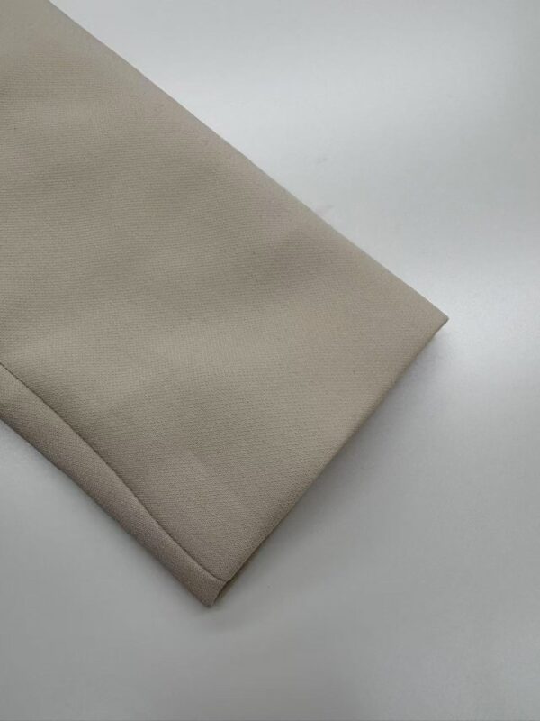 Close-up of beige fabric with folded edge, suitable for fashion or upholstery projects.