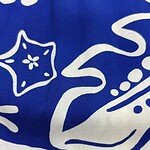 Close-up of blue fabric with white holiday-themed patterns including stars, swirls, and dots, suitable for Christmas or winter decorations.