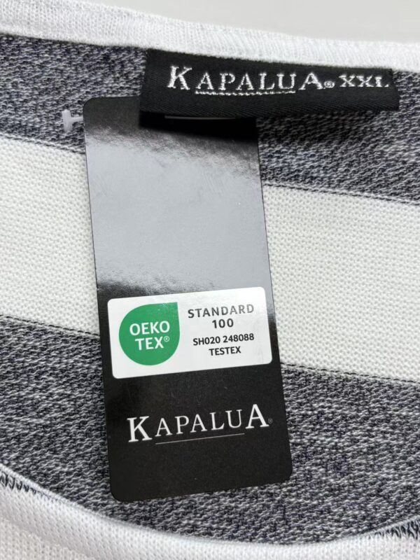 Close-up of Kapalua XXII clothing tag showing size and brand details on a striped fabric background.