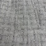 Detailed close-up of gray fabric with a textured pattern, showcasing a woven design with subtle sheen and intricate stitching.