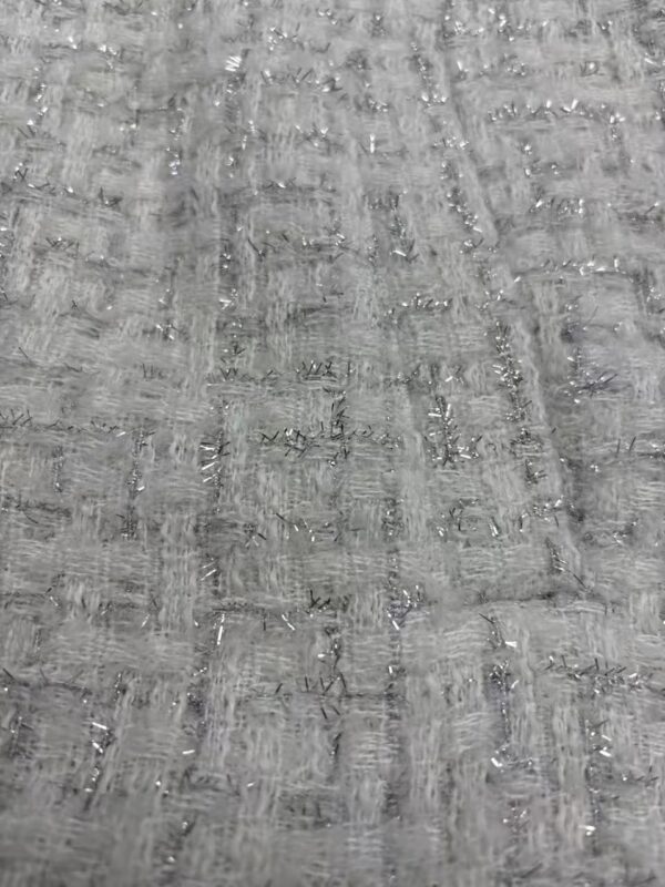 Detailed close-up of gray fabric with a textured pattern, showcasing a woven design with subtle sheen and intricate stitching.